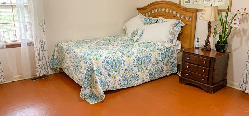 A cozy bedroom with a floral bedspread and wooden furniture.