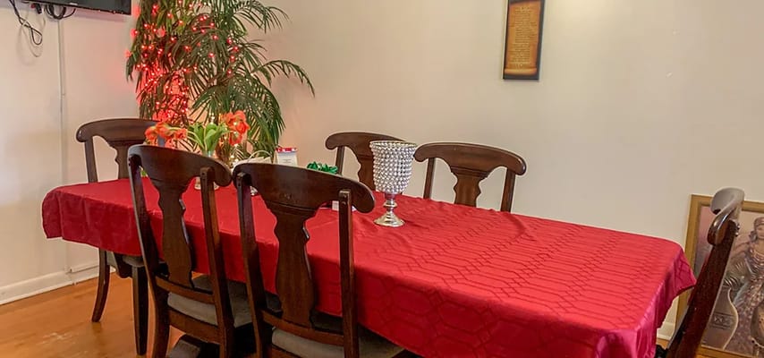 Red tablecloth on a dining table with floral decoration and chairs