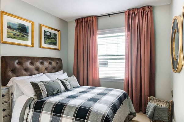 A well-decorated bedroom featuring a tufted headboard and patterned bedding.