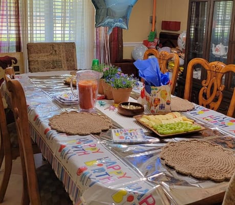 A decorated table for a birthday celebration with food and balloons.