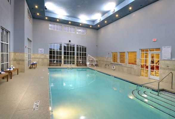Indoor swimming pool area with seating and natural light