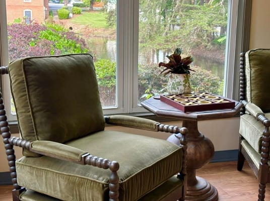 Comfortable green chairs by a window overlooking a garden