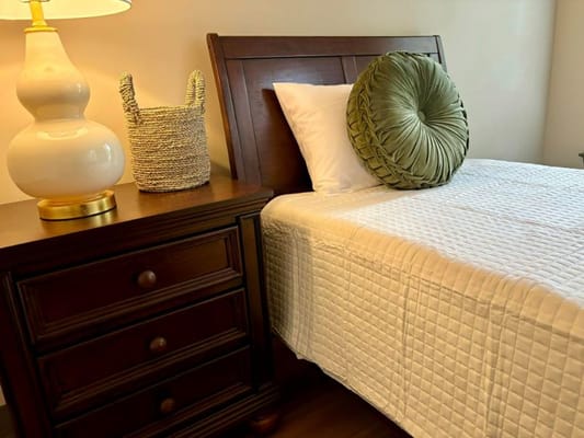 A neatly made bed with a decorative pillow and bedside lamp.