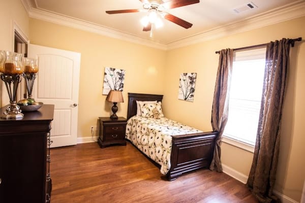 Sunny bedroom with a bed, dresser, and window.