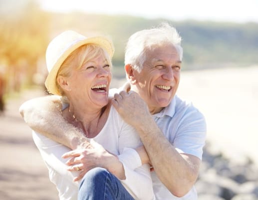 Elderly couple embracing and laughing outdoors
