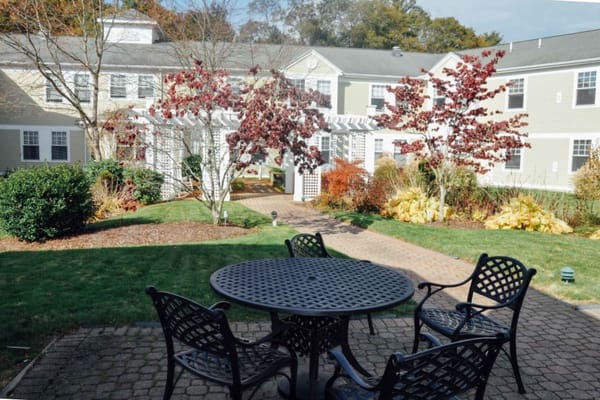 A patio table with chairs surrounded by landscaped garden at The Arbors at Taunton.