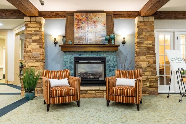 Two striped armchairs in front of a fireplace with stone accents.
