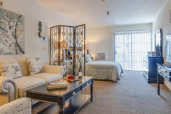 Well-furnished living room area with a bed in the background.