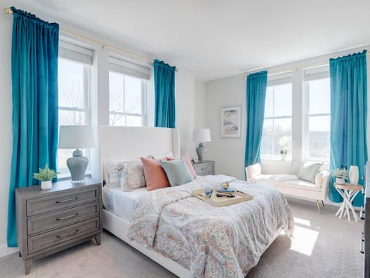 Bright bedroom with turquoise curtains and patterned bedding