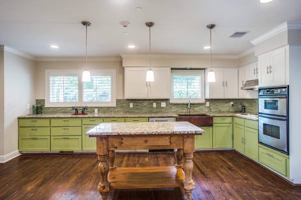 Modern kitchen with light green cabinets and granite countertops.
