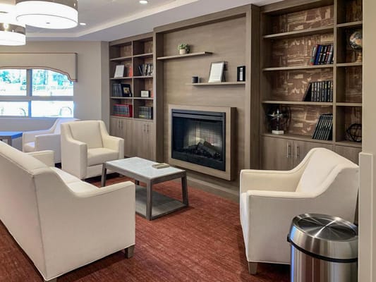 A cozy living room with white chairs, a coffee table, and a fireplace.