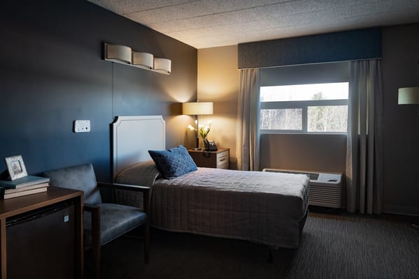 A comfortable bedroom with a bed, chair, and window.