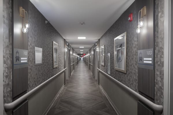 Long hallway with room numbers and artwork at The Sentinel of Port Jervis