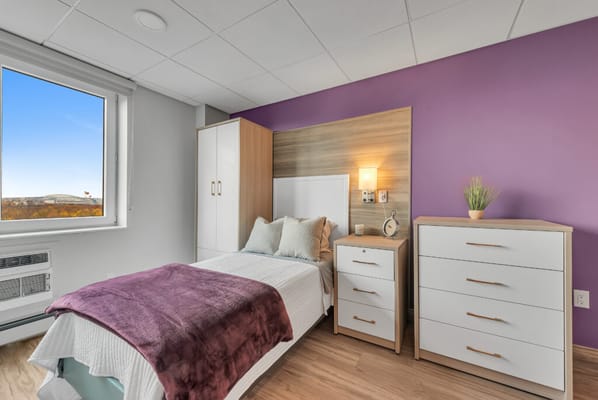A cozy bedroom with a view in The Veranda Assisted Living facility.