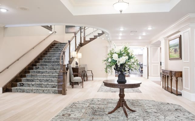 Elegant lobby with stairs, floral arrangement, and seating area at The Wellington at Lake Manassas.