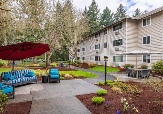 Outdoor seating area with blue striped couch and red umbrella