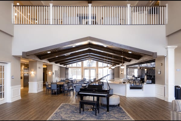 Spacious lounge area featuring a grand piano and dining tables.