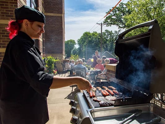 Staff grilling outdoors while residents enjoy a meal