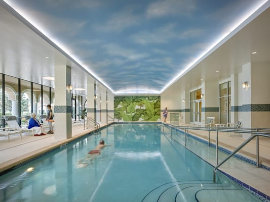 Indoor pool area with residents lounging and swimming