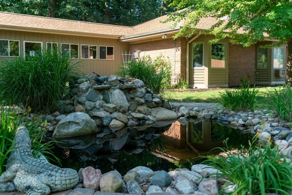 Exterior view of the facility with a pond and garden