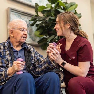 Staff member assisting a resident with weights in a communal area