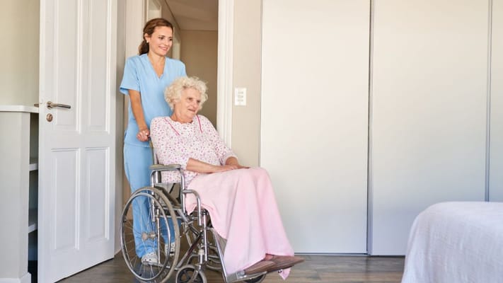 A caregiver assisting an elderly resident in a room