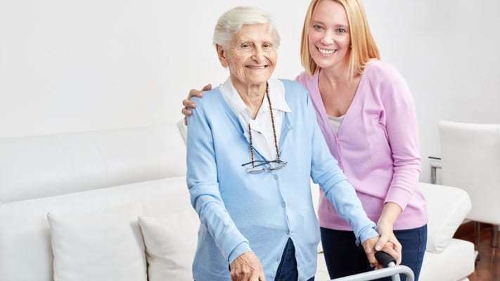 A smiling senior woman with her caregiver in a living room