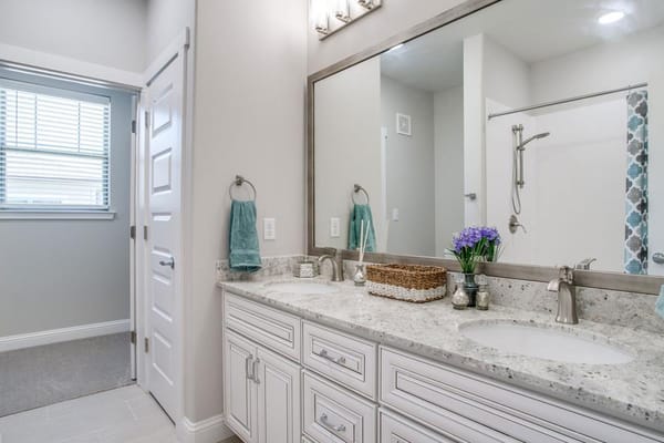 Bright bathroom with double sinks and decorative flowers