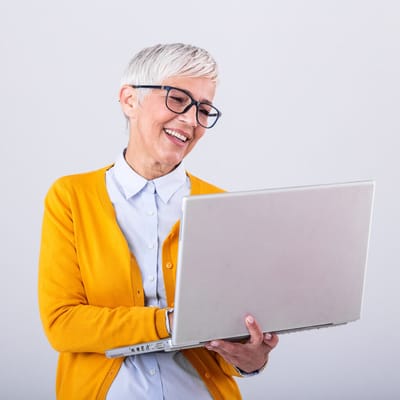 Older adult smiling while using a laptop