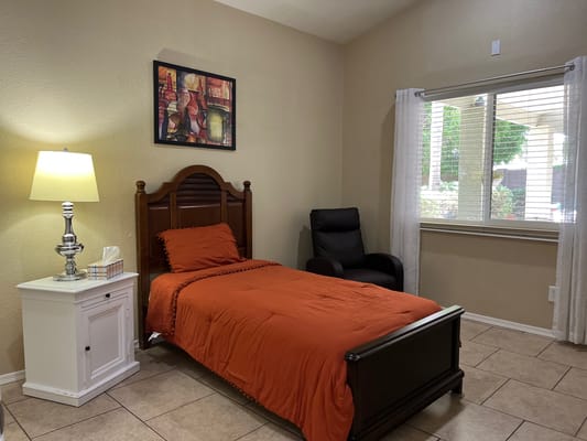 Cozy private room with orange bedding and a chair
