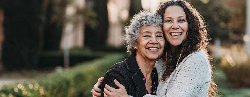 A senior resident and staff member smiling outdoors