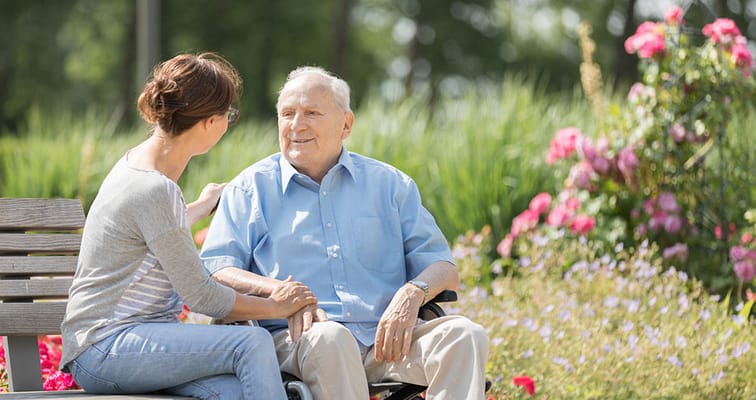Caregiver interacting with a resident in a garden.