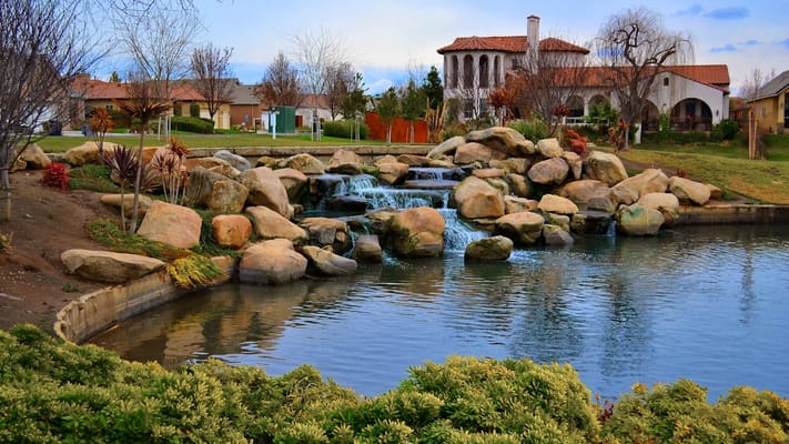 Water feature with rocks and greenery, facility building in background