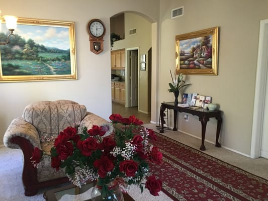 A cozy living room with floral arrangements and paintings.