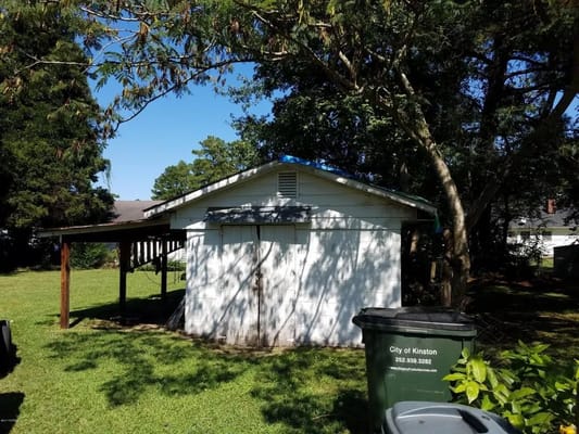 White shed surrounded by trees and grass