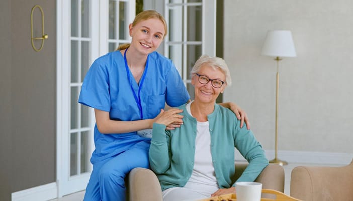 A caregiver smiling with a senior resident in a common area