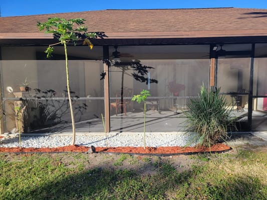 View of the screened veranda with plants and seating area