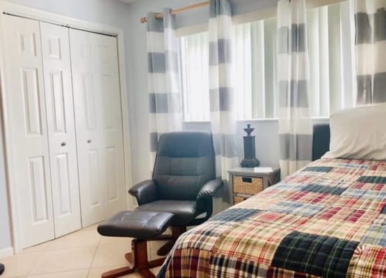 Bedroom featuring a bed, chair, and curtains