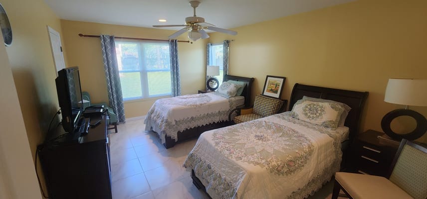 A bright, cozy bedroom with two twin beds and a TV.