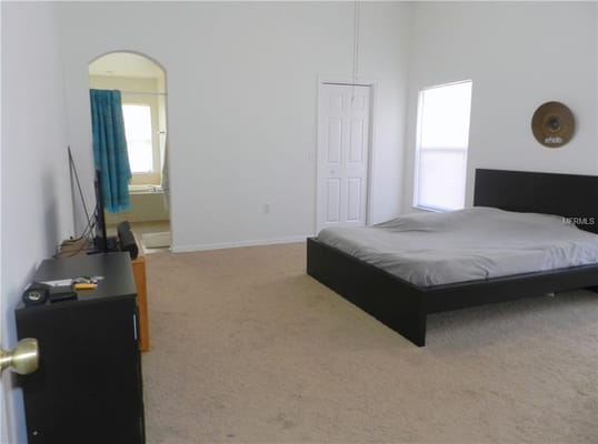 Bright bedroom with a bed and television