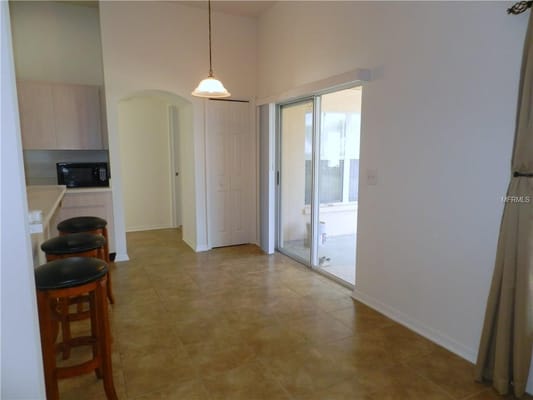 An interior view of the kitchen area with bar stools and microwave.