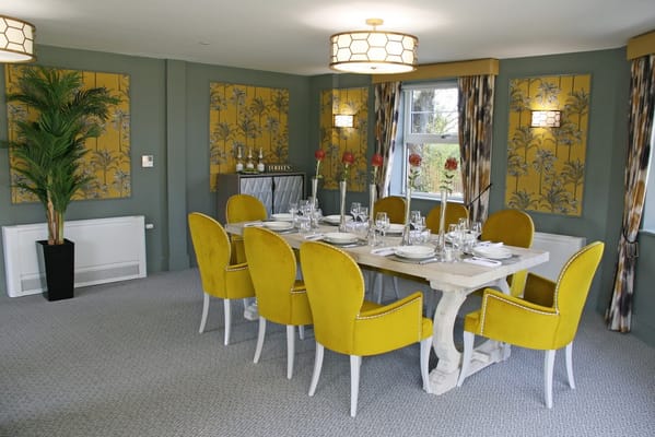 Elegant dining room with yellow chairs and floral wallpaper