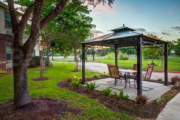 Outdoor gazebo with seating in a landscaped area