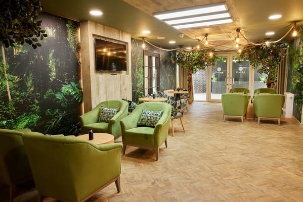 Interior lounge area with green chairs and plants