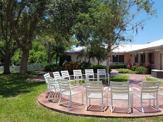 Outdoor seating area with white chairs near the facility.