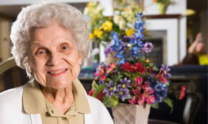 Senior resident smiling with colorful flowers in the background