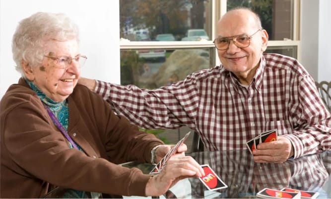 Two residents enjoying a game of Uno at a table