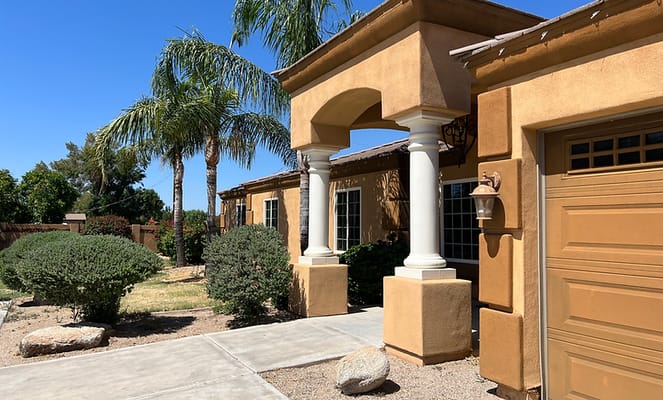 Front entrance of Mayfair Eden Homes with palm trees and shrubs