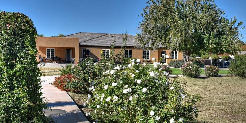 A well-maintained garden with flowers in front of the Mayfair Eden Homes facility.