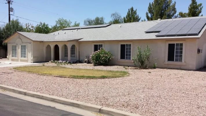 Front view of Mesa Elder Care facility with desert landscaping and solar panels.